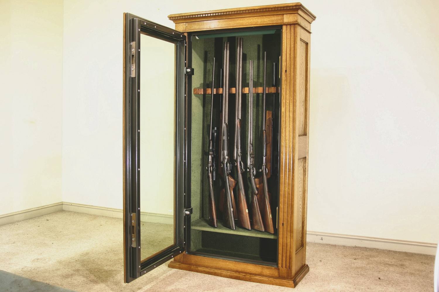 Glazed gun cabinets in oak, door open, showing guns racked on green baize