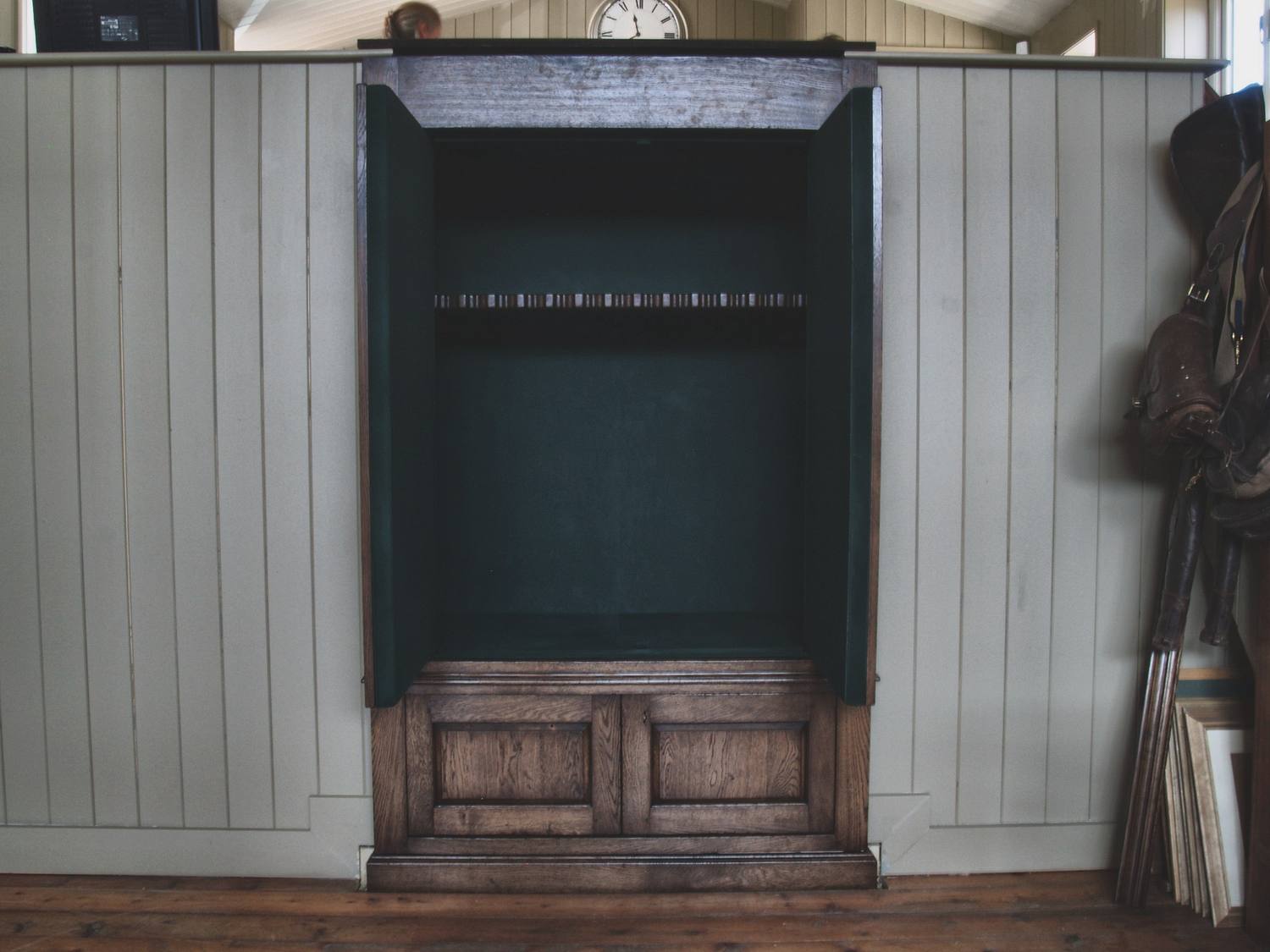 Fitted gun cabinets built into painted panelling, with a teal-lined interior