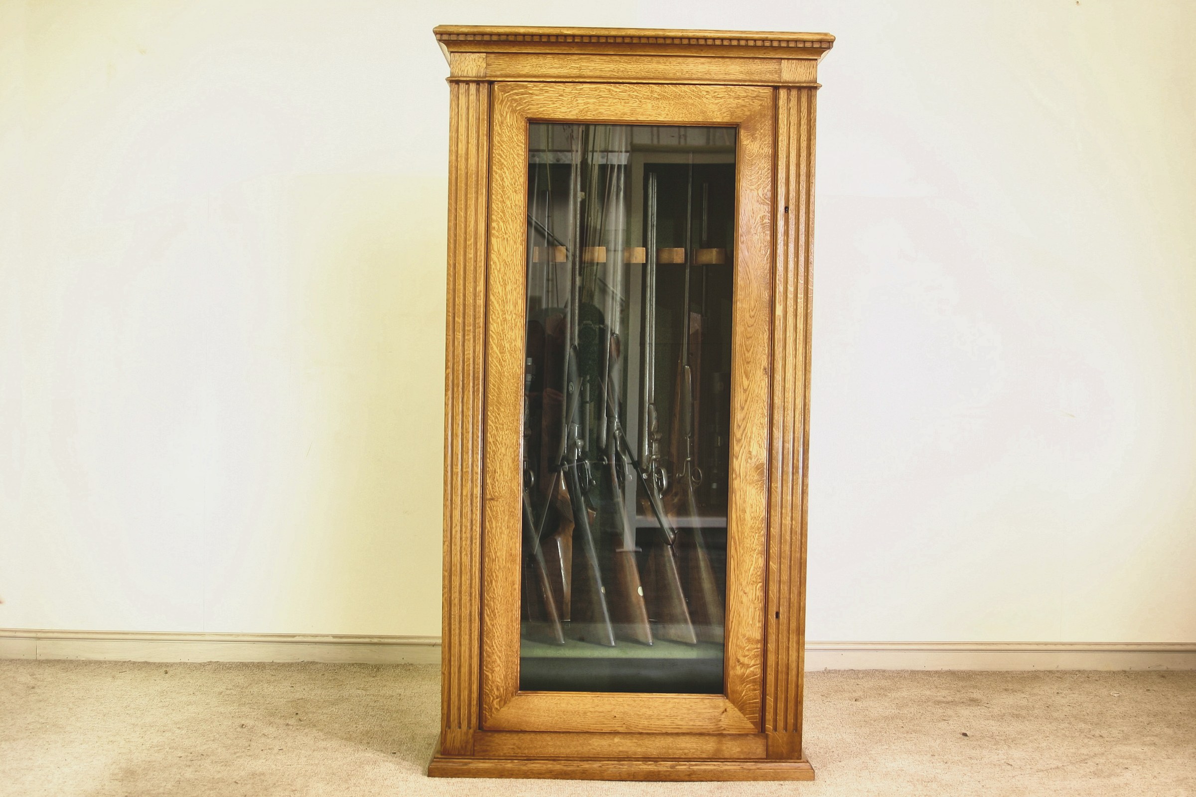 A bespoke glazed oak gun cabinet in solid oak