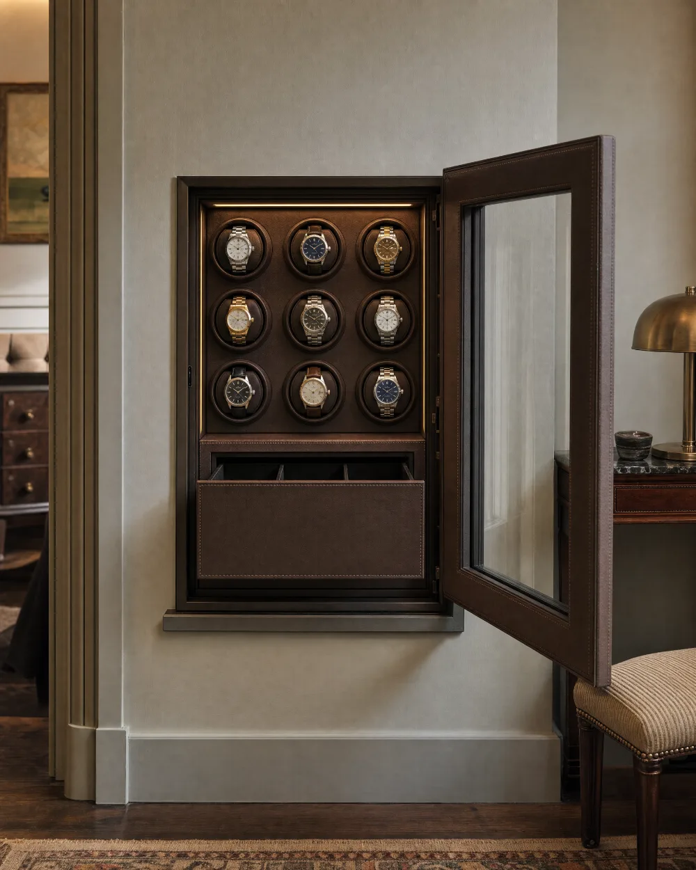 Compact wall-recessed watch safe with a leather-faced glazed door standing open, nine lit winder positions and a leather-lined drawer below